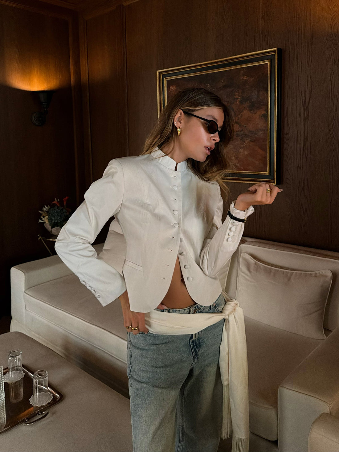 Sasha in a white jacket and denim in a wood-panelled Paris room